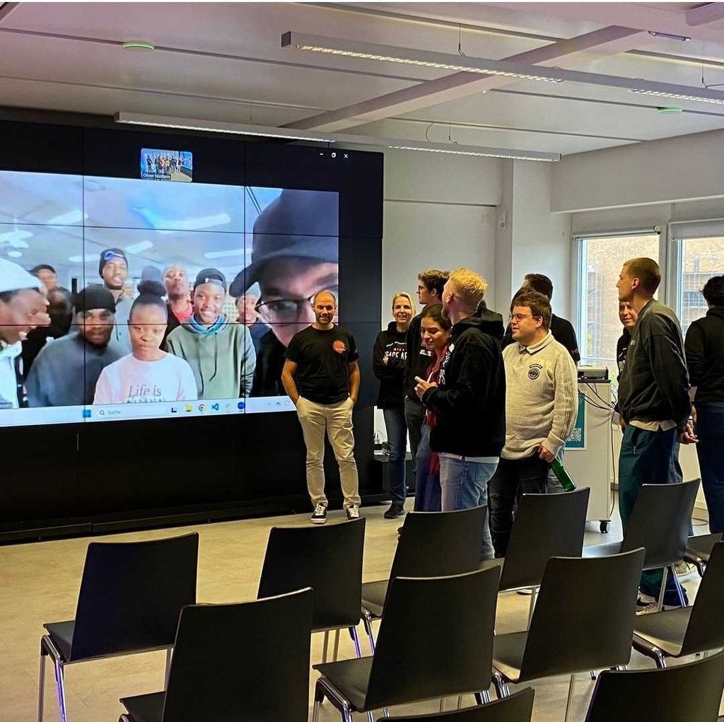 Group of people video chatting on a large screen with other people